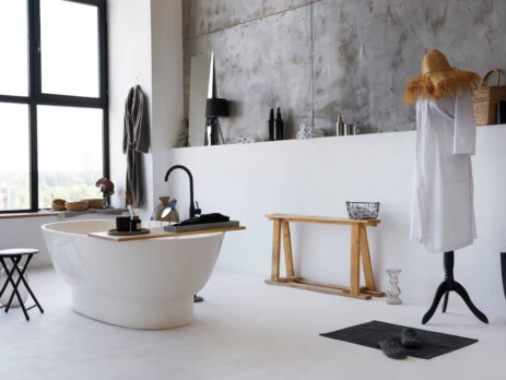 Widok z boku na zaprojektowaną łazienkę w jasnych kolorach z wanną wolnostojącą i nowoczesną armaturą