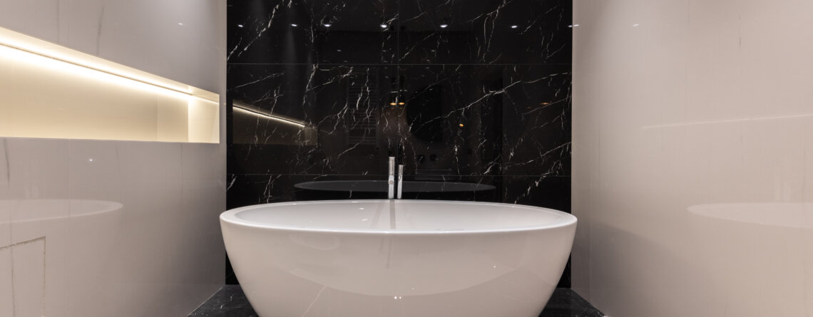 Czarno-biała łazienka z płytkami na wysoki połysk i wanną wolnostojącą