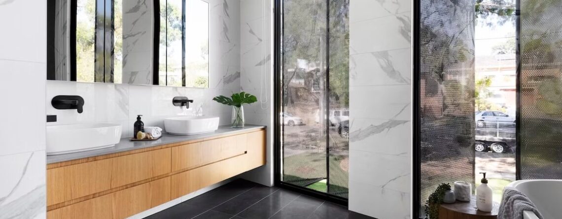 Ciepła, nowoczesna łazienka z wanną, brązowymi szafkami podumywalkowymi i lustrami p0owiększającymi wnętrze